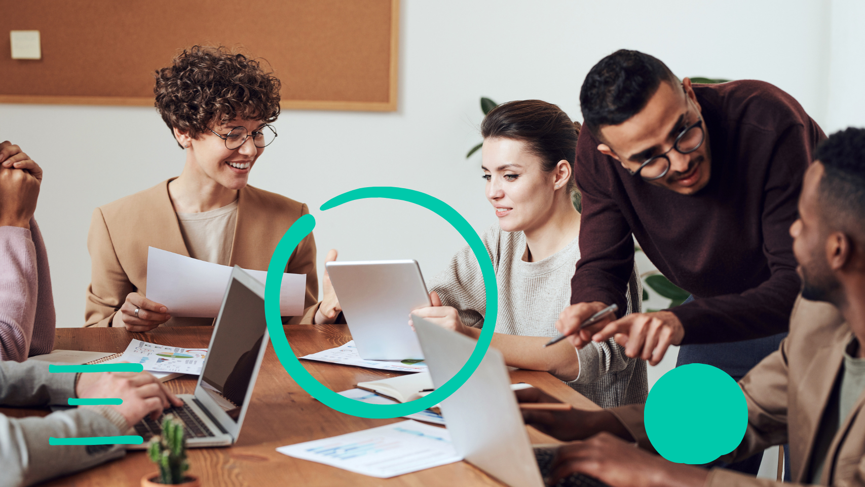 a group of people sitting around a table with laptops